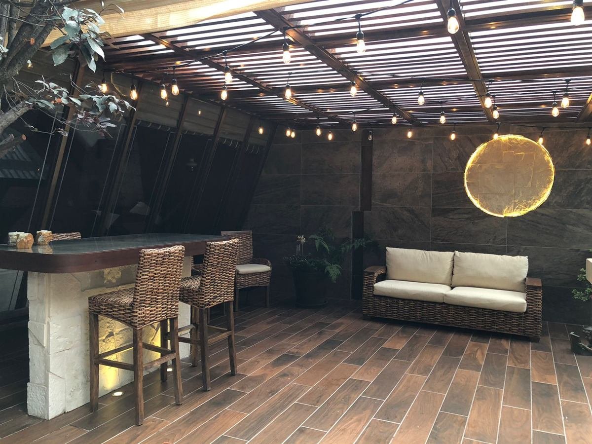 Terraza remodelada de Casa Crisantemo con pérgola de madera, barra y sala exterior